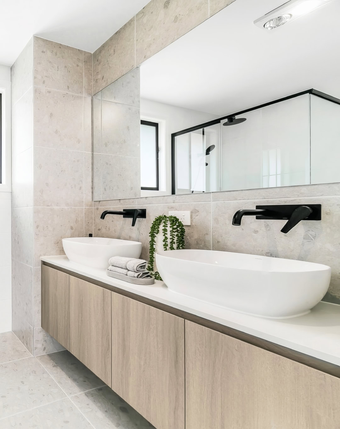 Stunning modern bathroom with wood grain cabinetry, matte black accents and a large double vanity